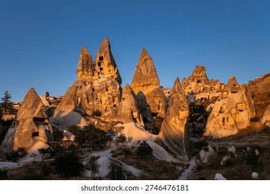 Illuminated by the last rays of the setting sun fairy chimneys with the homes carved in a cliffs near Uchisar castle in Cappadocia, Turkey.