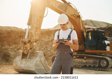 Illuminated by sunlight. Worker in professional uniform is on the borrow pit at daytime.