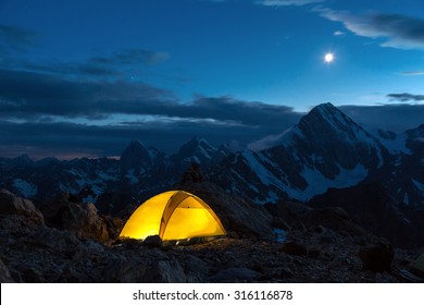 Illuminated Camping Yellow Tent Night High Altitude Alpine Landscape Shining Moon In Dark Blue Sky 