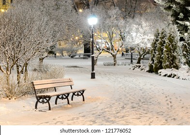 Illuminated city park at night. Bench and lantern close-up. Snow-covered trees after a blizzard. Dark atmospheric winter cityscape. Tourism, recreation, Christmas, vacations, downtown. Panoramic view - Shutterstock ID 121776052