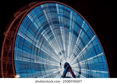 Illuminated defocused blue Christmas ferris wheel against the night sky. Blurred motion ferris wheel with Christmas lights. Horizontal long exposure photography. - Powered by Shutterstock