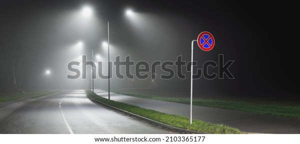 Illuminated empty\
highway in a fog at night. Street lights and road signs close-up.\
Dark urban scene, cityscape. Riga, Latvia. Dangerous driving,\
speed, freedom, concept\
image