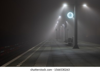 Illuminated, empty platform at a railroad station during a foggy night in autumn. - Powered by Shutterstock