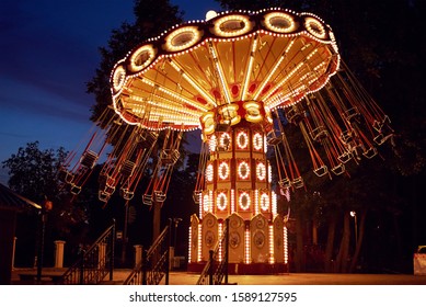 Illuminated Ferris Wheel In Amusement Park At Night City