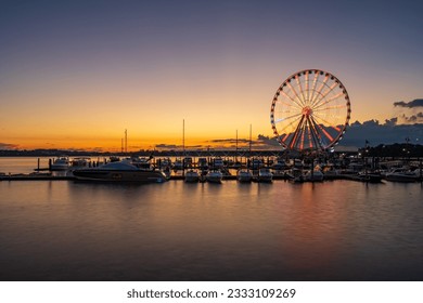 Illuminated ferris wheel at National Harbor near the nation capital of Washington DC at sunset with marina in the foreground - Powered by Shutterstock
