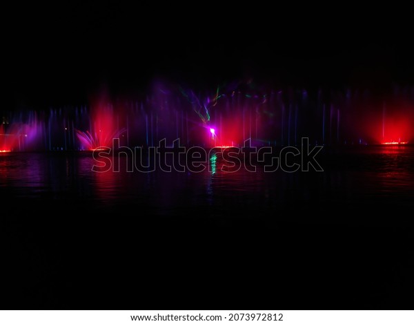 illuminated fountains\
above the water at\
night