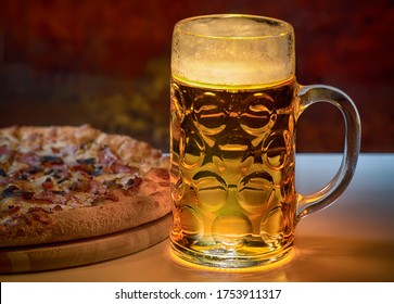 Illuminated glass mug or tankard of golden ale or beer served with a fresh crusty Italian pizza for a pub lunch - Powered by Shutterstock