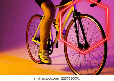 Illuminated hexagon over low section of caucasian male athlete riding bike on purple background. Copy space, composite, sport, cycling, racing, competition, leg, shoe, shape and abstract concept. - Powered by Shutterstock