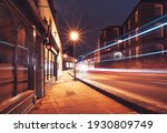Illuminated High Street of Harrow on the Hill with a passing bus and cars in motion, Greater London, England 