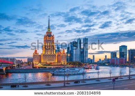 Illuminated high-rise stalinist building near river at evening in Moscow, Russia. Historic name is Hotel Ukraine. Spring or summer urban cityscape.