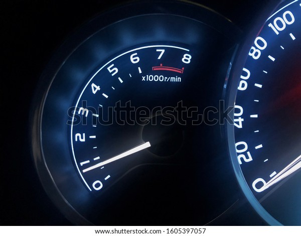 Illuminated image\
of car tachometer with reading less than 1000 RPM. Slight view of\
speedometer can also be\
seen.