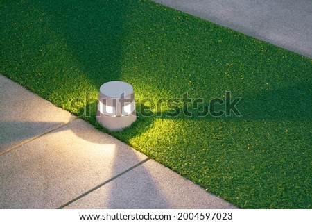 Illuminated LED Ground Lantern on Artificial Turf and gravel stone walkway in Front Yard area