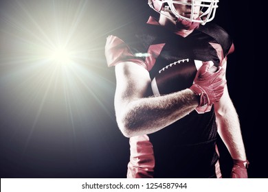 Illuminated light against american football player in helmet holding rugby ball - Powered by Shutterstock