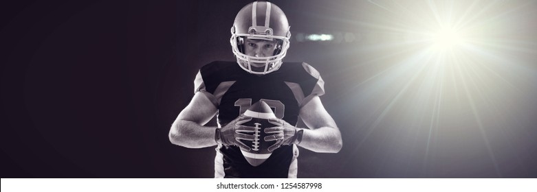 Illuminated light against american football player in helmet holding rugby ball - Powered by Shutterstock