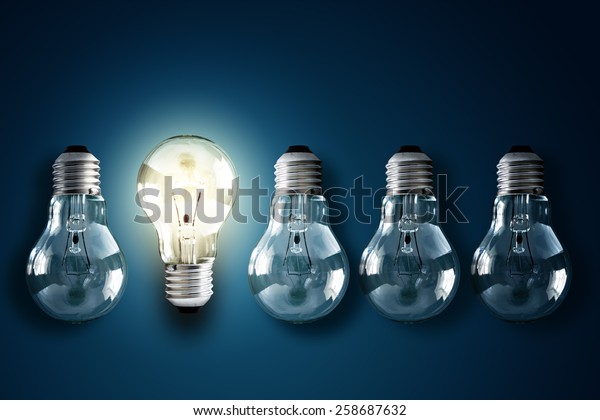 Illuminated light bulb in a row of dim ones\
concept for creativity, innovation and\
solution