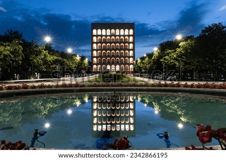 The illuminated Palazzo della Civilta Italiana and its reflection in the pond in Rome, Italy