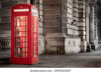 Illuminated red vintage London phone booth on a sidewalk in Westminster. Photo taken in the evening in London United Kingdom - Powered by Shutterstock