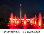 Illuminated red water on Poklonnaya Hill. Night colored fountains in urban public park, Moscow, Russia. Alley of fiery red fountains on memorial Victory Alley with the background of the Stella.