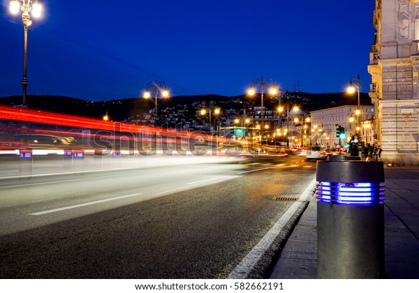 Illuminated road along Daugava river and railway\
bridge at night in\
Italy
