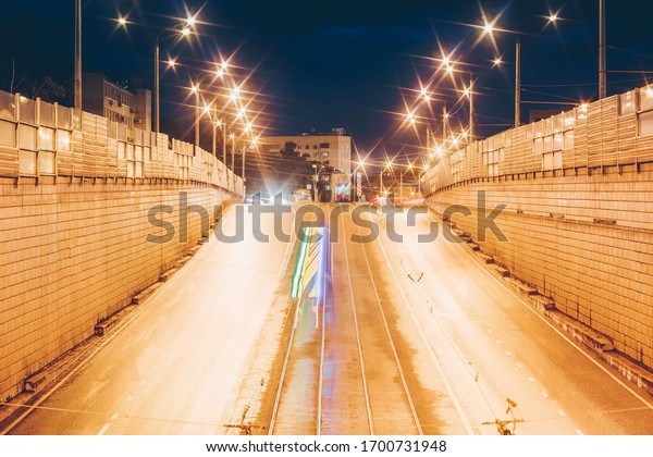 Illuminated road with rails at night. Light of city\
lanterns. 