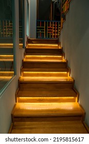 Illuminated staircase with wooden steps and illuminated at night in the interior of a large house.