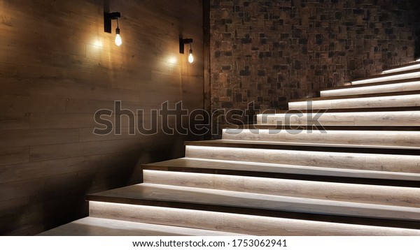 Illuminated staircase with\
wooden steps and illuminated at night in the interior of a large\
house