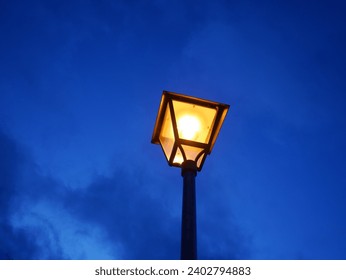 Illuminated street lamp against of evening cloudy sky. Copy space.