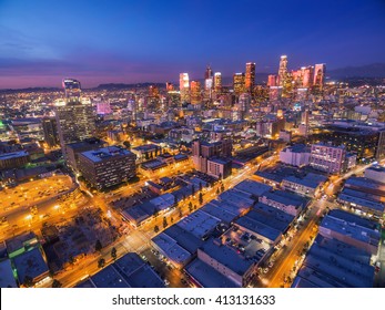 Illuminated Streets Leading To Downtown Los Angeles Skyline At Twilight Dusk Night. Aerial Perspective.