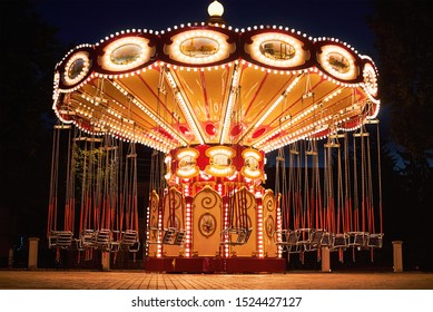 Illuminated swing chain carousel in amusement park at night