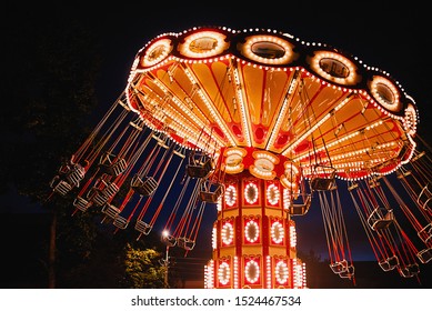 Illuminated swing chain carousel in amusement park at night - Powered by Shutterstock