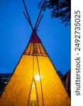 Illuminated tipi tent glowing warmly against the evening sky, creating a cozy and inviting atmosphere at a peaceful campsite.