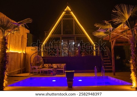 The illuminated version and pool of the bungalow in the forest