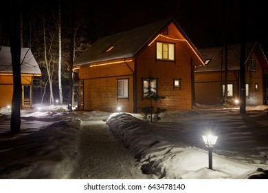 Illuminated wooden houses on winter evening among trees. - Powered by Shutterstock