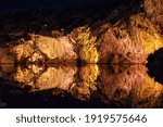 illumineted caves miroring in still waters of vouliagmeni lake in the night