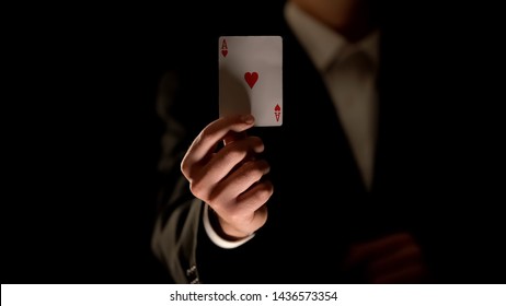 Illusionist Showing Ace Of Heart Card At Camera, Magic Trick, Black Background