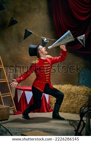 Illusionist or showman. Cinematic portrait of emotive man retro circus entertainer announces start of show isolated over dark retro circus backstage background. Concept of emotions, art, sales