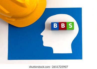 Illustration for Behavior-Based Safety (BBS) featuring safety helmet along with  a paper-cut human head with blue, red and green blocks, labeled BBS