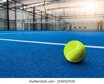 Illustration of green ball for padel game placed on blue surface with white lines in spacious light court glowing light and net - Shutterstock ID 2145527619