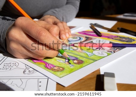 Illustrator draws comic book frames on paper. The artist designer creates the characters.