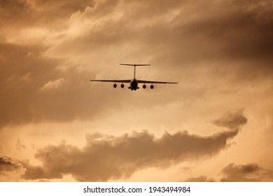 Ilyushin Aircraft Seen From Behind During Take Off At Low Altitude In A Vintage Photo Effect. Russian Four-engine Airplane Silhouette In A Gold Color. Russian Plane Constructor.