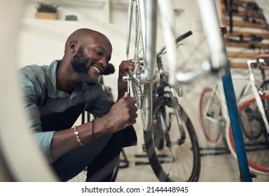 Im almost done fixing this. Shot of a handsome young man crouching alone in his shop and repairing a bicycle wheel. - Powered by Shutterstock