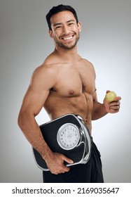 Im doing everything I can to maintain a healthy weight. Shot of an athletic young man holding an apple and a weighing scale.
