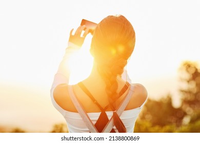 Im glad I get to capture this amazing view. Rearview shot of an unrecognizable woman taking a photo using her cellphone in nature. - Shutterstock ID 2138800869