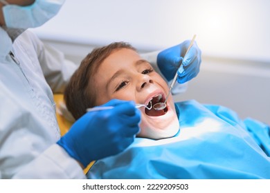 Im going to have a bright smile after this. Shot of a young little boy lying down on a dentist chair while getting a checkup from the dentist. - Powered by Shutterstock