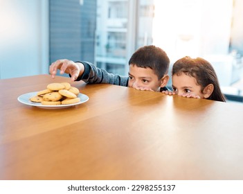 Im going in, cover me sis. two mischievous young children stealing cookies on the kitchen table at home.