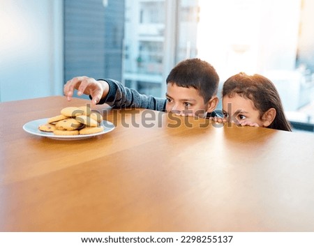Im going in, cover me sis. two mischievous young children stealing cookies on the kitchen table at home.