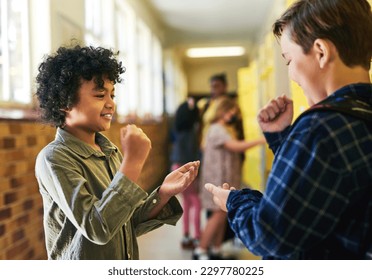 Im going to win this one. two young boys standing in the school hallway together and playing a game of rock, paper and scissors. - Powered by Shutterstock