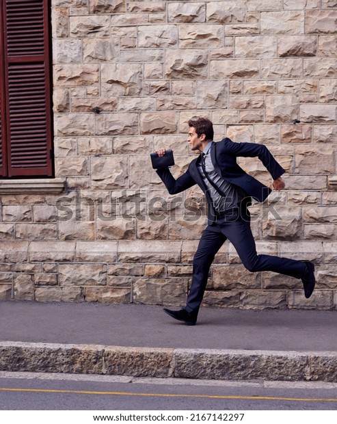 Im late. Shot of a young businessman running down\
a street.