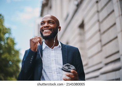 Im listening to my favourite motivational speaker. Shot of a businessman holding a coffee and listening to music through earphones while walking through the city. - Powered by Shutterstock