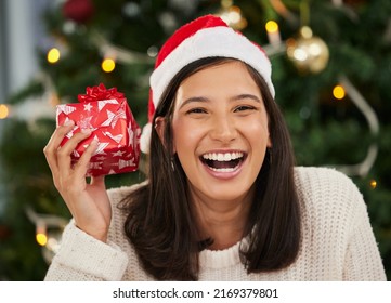 Im Not One To Wait To Open My Gifts. Shot Of A Young Woman Holding A Gift Box At Home During Christmas Time.